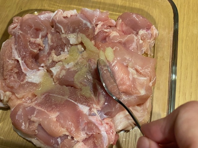 鶏肉にニンニクとショウガを塗っている